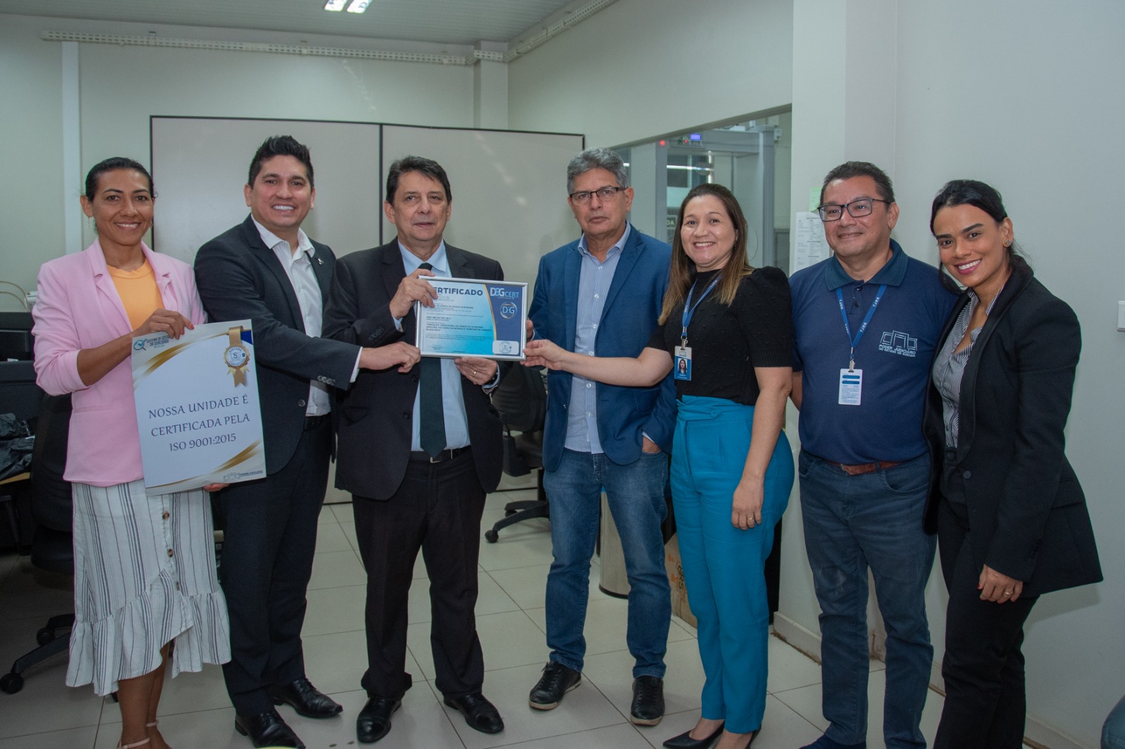 Foto colorida mostra sete pessoas posando para a foto. Ao centro, o desembargador Jésus Nascimento, o juiz Marcelo Lima e o juiz Parima Dias, todos segurando a certificação