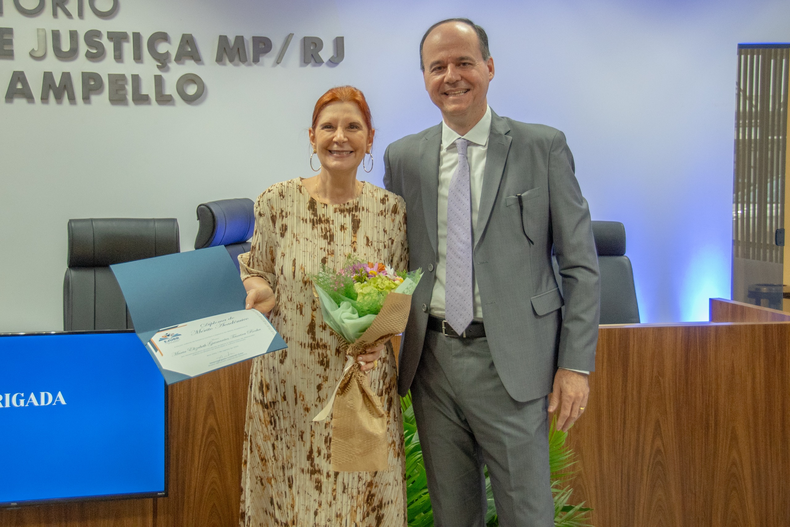 Foto colorida mostra a ministra do Superior Tribunal Militar (STM), Maria Elizabeth Rocha, posando para foto ao lado do diretor da Ejurr, desembargador Cristóvão Suter, no Fórum Criminal Ministro Evandro Lins e Silva.