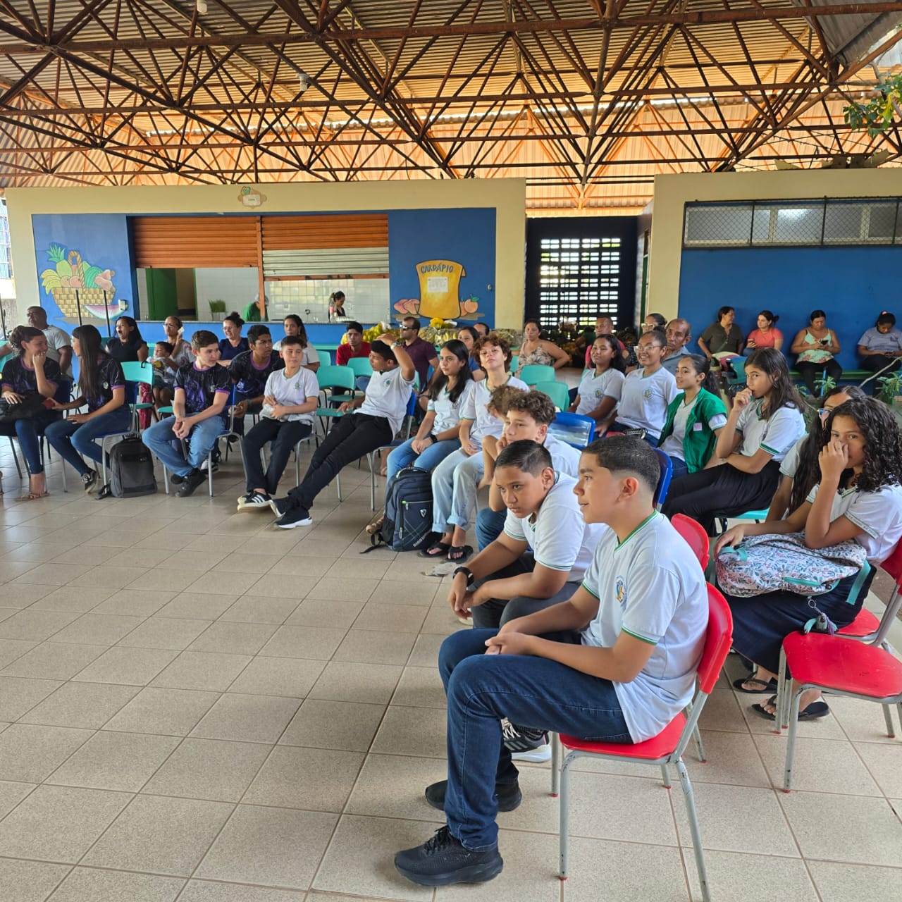 Imagem colorida contém diversos alunos sentados em volta de uma roda de conversa no pátio da escola. Abaixo a frase “PROMOÇÃO DA PAZ SOCIAL - Justiça Comunitária do TJRR encerra 2024 com resultados expressivos no 4º trimestre.