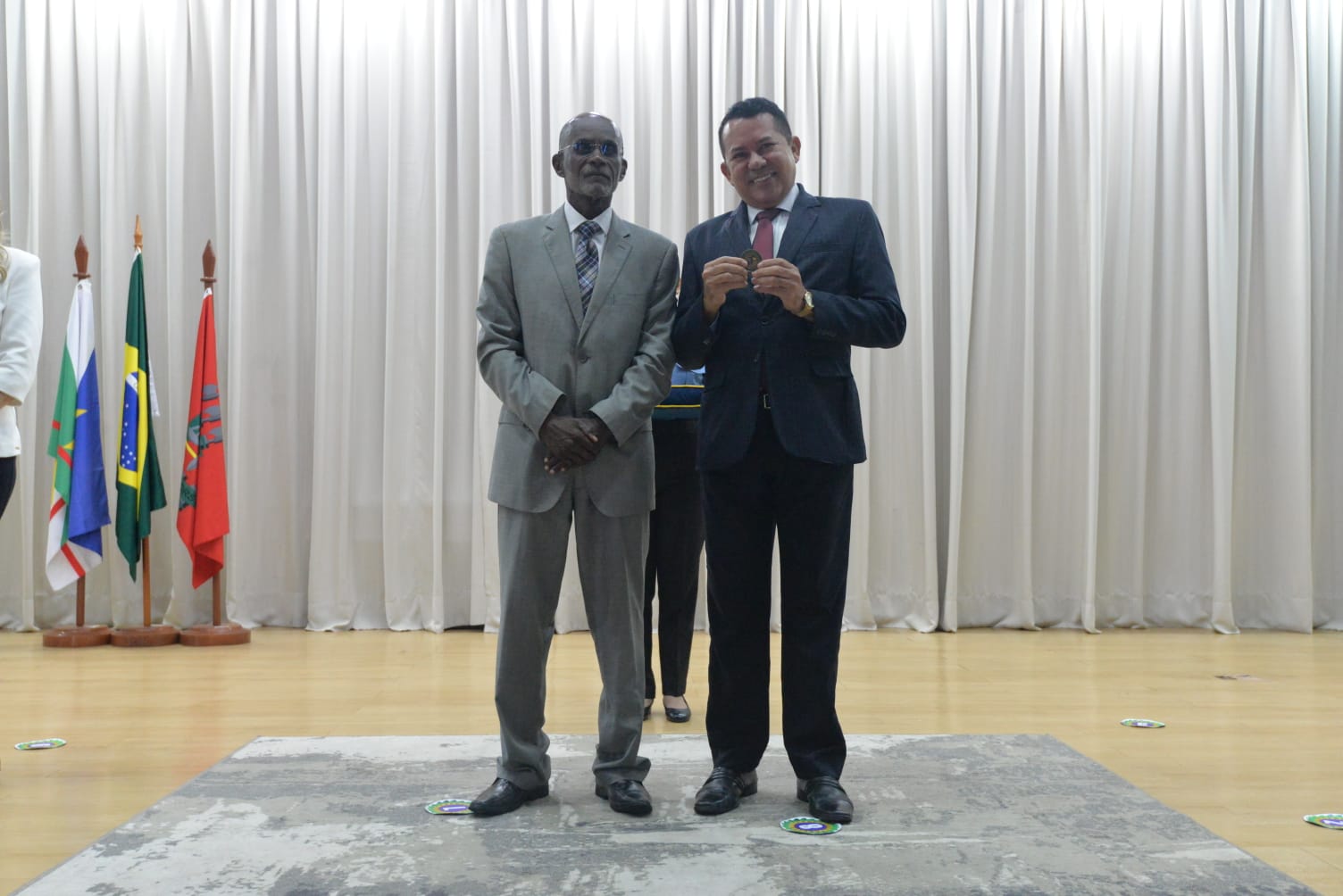 Foto colorida mostra duas pessoas em pé posando para foto. O desembargador Audaliphal Hildebrando da Silva e o analista judiciário Walterlon Azevedo Tertulino