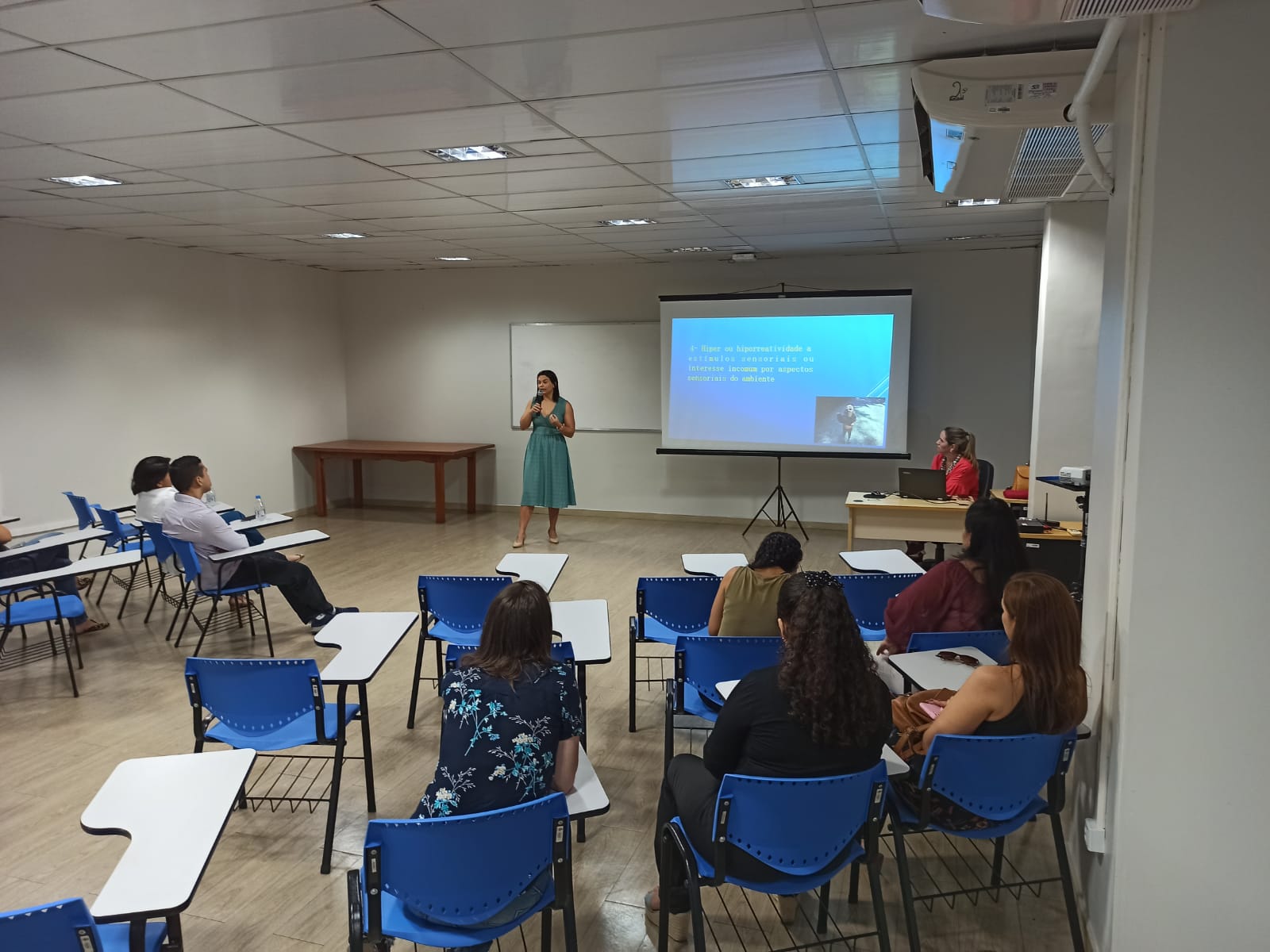 Imagem colorida contém servidores do TJRR, sentados assistindo palestra de conscientização sobre o autismo, organizado pelo Centro Médico e Qualidade de Vida, com palestrante em pé aos participantes.