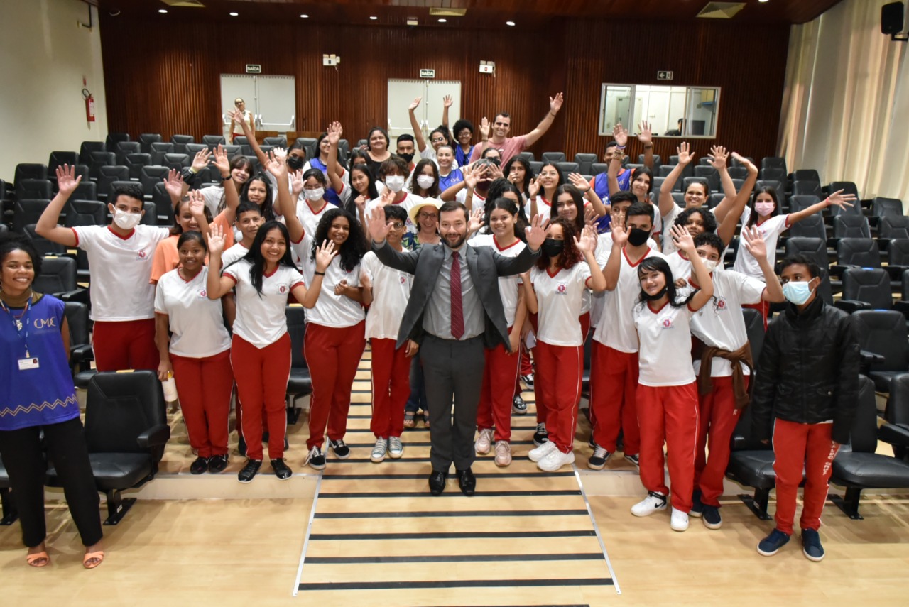 Imagem colorida dos alunos da Escola Estadual Oswaldo Cruz, juntamente com o Juiz auxiliar do TJRR, Dr Bruno Fernandes Alves Costa, e servidores do TJRR, posando posando para fotografia, no Tribunal do Pleno do TJRR.