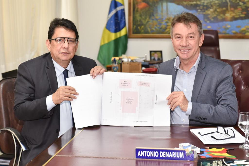 foto colorida do Presidente do TJRR, des Jésus Nascimento   juntamente com o Governador Antonio Denarium pousando para a foto. Ambos estão segurando um papel
