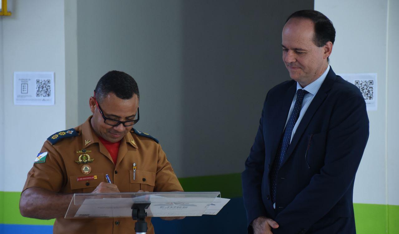 FOTO COLORIDA COM O DESEMBARGADOR CRISTOVÃO SUTER AO LADO ,TENENTE- CORONEL Genivaldo Vasconcelos que está assinando papeis de acordo 