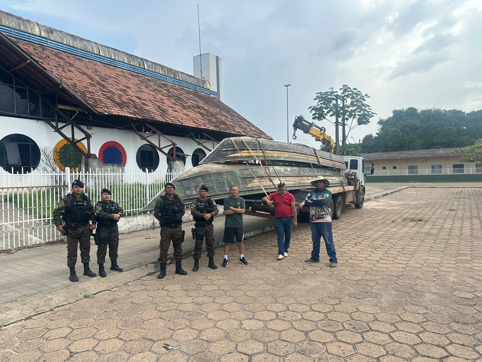 foto colorida na frente do predio Latine Salomão com policiais pousando para foto com dois barcos atraz 