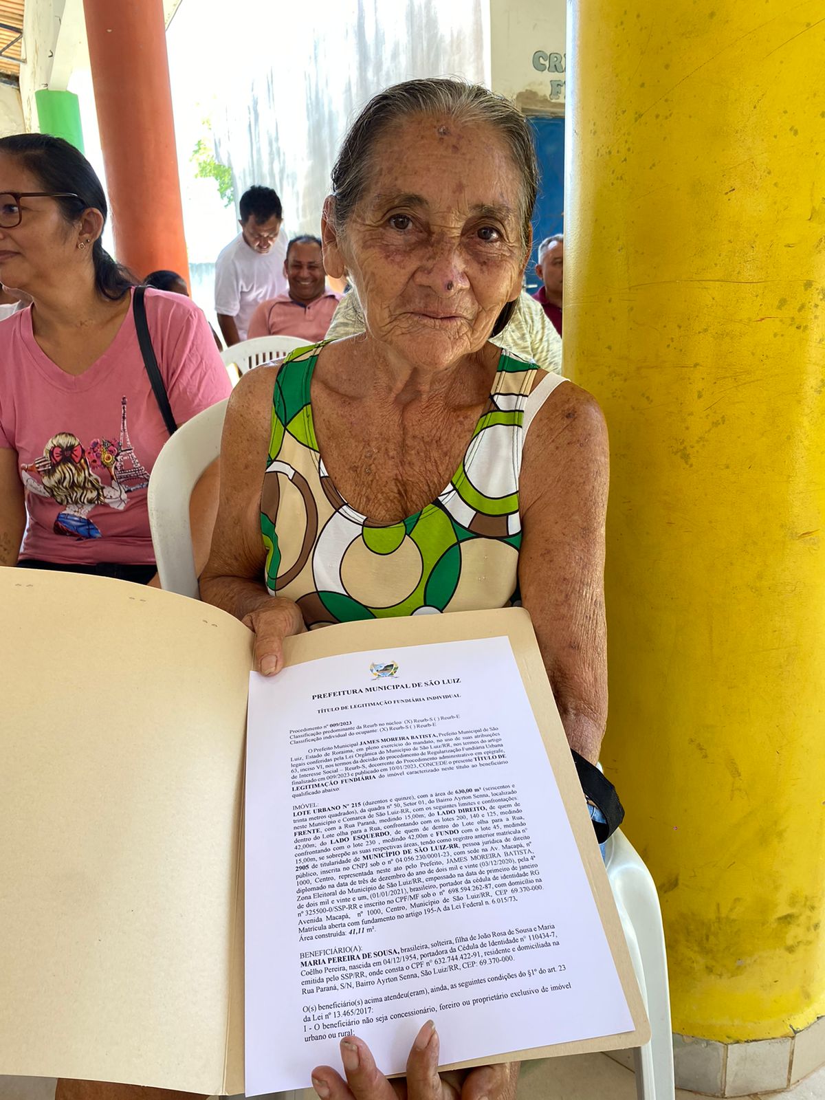 foto colorida de uma idosa mostrando seu titulo e sorrindo