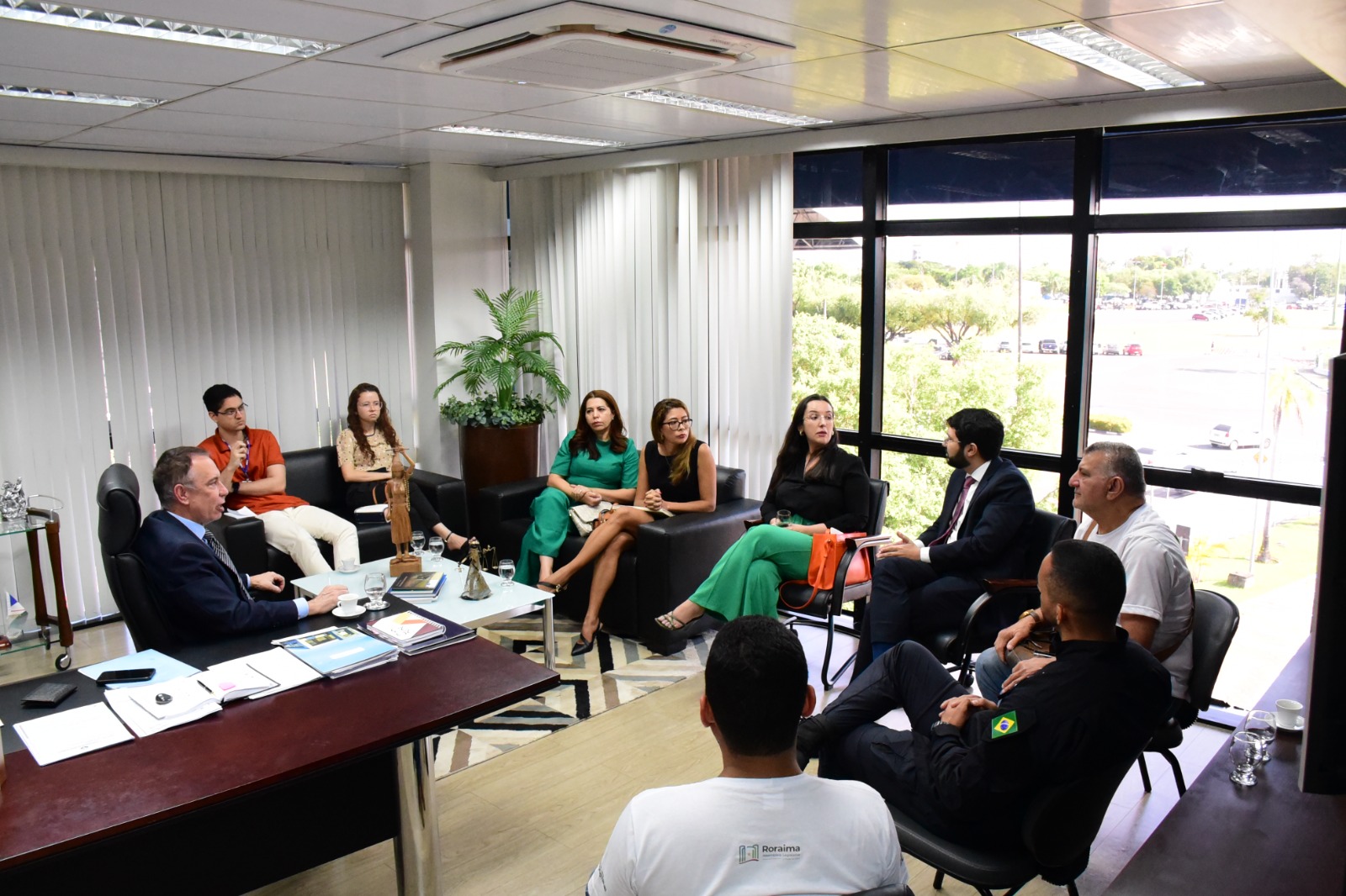 foto colorida na horizontal em área interna de uma sala onde todos estão sentados formando uma roda semi aberta. Estão presentes na imagem o  desembargador Almiro Padilha, supervisor do GMF/TJRR, o secretário da Sejuc, Hércules Pereira, do juiz titular da VEP,  Daniel Damasceno Amorim, a coordenadora estadual da Mulher em Situação de Violência Doméstica e Familiar do Tribunal de Justiça de Roraima, juíza Suelen Alves,  da Diretora da Procuradoria Especial da Mulher da Assembleia Legislativa de Roraima, Glauci Gembro e representantes do Centro Humanitário da Mulher (Chame)