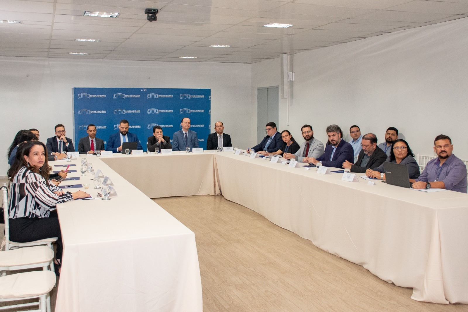 Imagem colorida mostrando pessoas reunidas em uma sala durante reunião