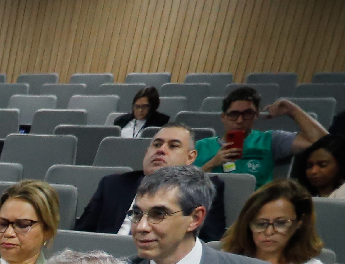 Foto colorida mostrando pessoas sentadas em um auditório 