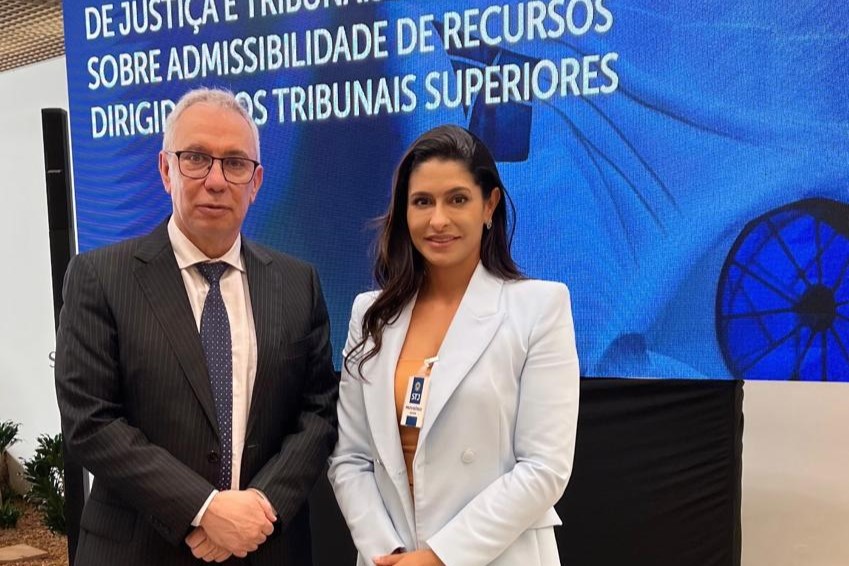 Na imagem, duas pessoas estão posando para uma foto em frente a um banner, o Desembargador Almiro Padilha, atual Vice-Presidente deste Tribunal de Justiça de Roraima (TJRR), e a Assessora Chefe da Unidade, Greci Mara. À esquerda, um homem de óculos, terno escuro e gravata clara com desenhos escuros está com as mãos cruzadas à frente. À direita, uma mulher com um blazer azul claro, uma blusa clara por baixo e uma saia laranja está com as mãos juntas à frente. Na imagem, duas pessoas estão posando para uma foto em frente a um banner, o Desembargador Almiro Padilha, atual Vice-Presidente deste Tribunal de Justiça de Roraima (TJRR), e a Assessora Chefe da Unidade, Greci Mara. À esquerda, um homem de óculos, terno escuro e gravata clara com desenhos escuros está com as mãos cruzadas à frente. À direita, uma mulher com um blazer azul claro, uma blusa clara por baixo e uma saia laranja está com as mãos juntas à frente.