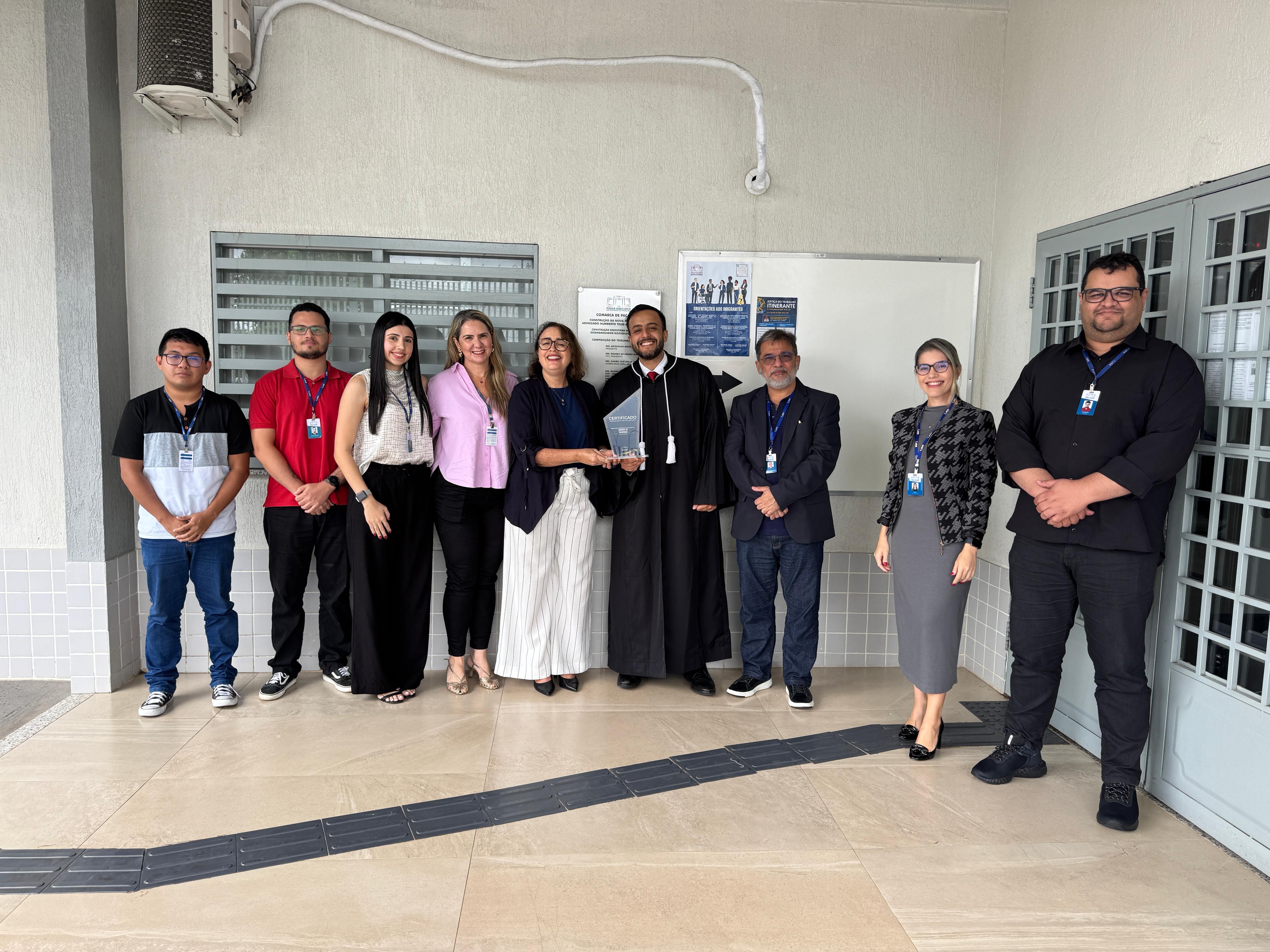 imagem colorida contém o Juiz titular da Comarca de Pacaraima, Phillip Barbieux Sampaio posando para fotografia ao lado da Juíza Auxiliar da Presidência, Lana Leitão Martins, do Secretário-Geral, Hermenegildo Ataíde D’Ávila; da Subsecretária de Processos e Gestão da Qualidade, Erika Horta; e mais cinco servidores da Comarca de Pacaraima, segurando uma placa condecodativa do ISO 9001. imagem colorida contém o Juiz titular da Comarca de Pacaraima, Phillip Barbieux Sampaio posando para fotografia ao lado da Juíza Auxiliar da Presidência, Lana Leitão Martins, do Secretário-Geral, Hermenegildo Ataíde D’Ávila; da Subsecretária de Processos e Gestão da Qualidade, Erika Horta; e mais cinco servidores da Comarca de Pacaraima, segurando uma placa condecodativa do ISO 9001.