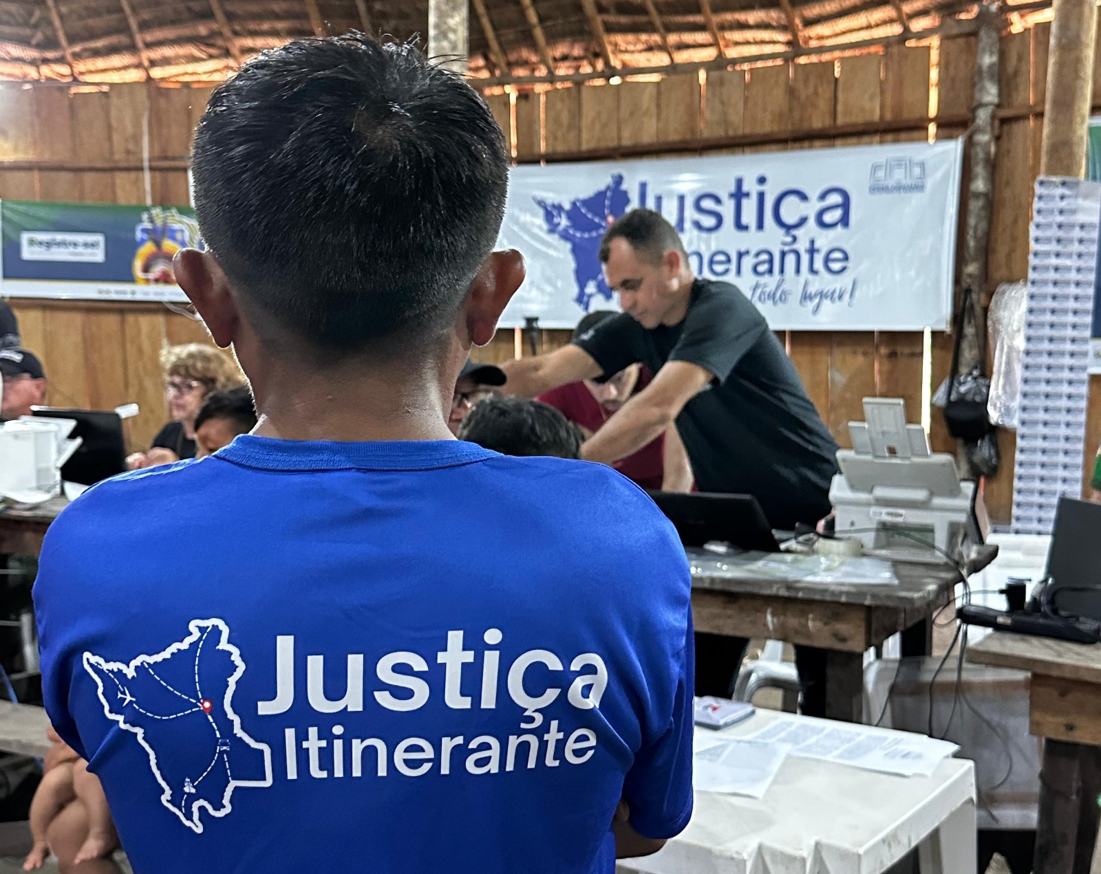 Foto colorida de uma pessoa com a camisa da justiça itinerante de costa