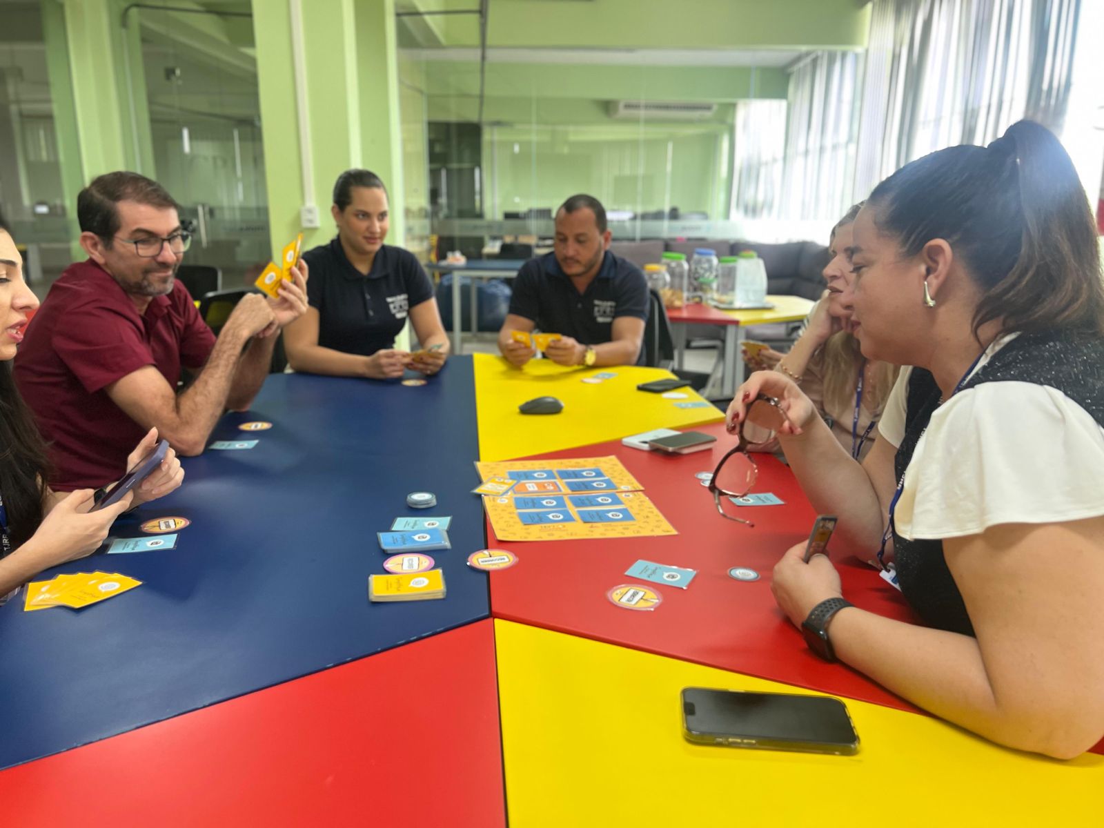 Foto 1: imagem colorida de um grupo pessoas reunidas no Núcleo de Projetos e Inovação durante uma oficina. 