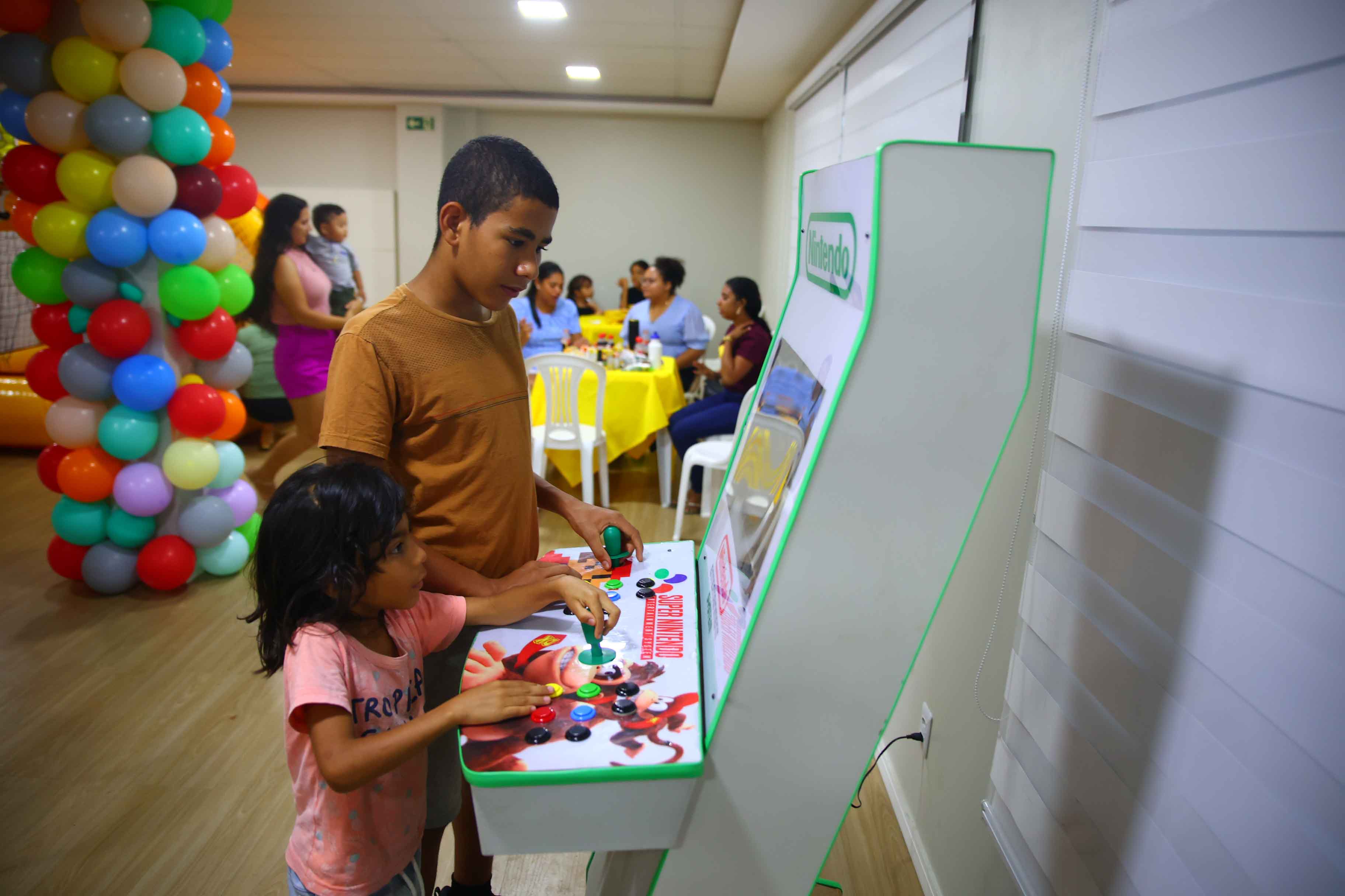 Imagem colorida de duas crianças brincando em uma maquina de jogos