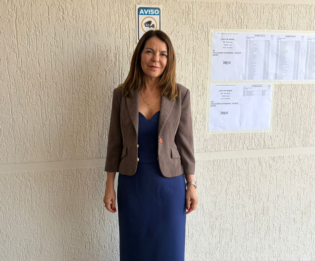 Imagem pousada da  juíza da Comarca de Bonfim, Liliane Cardoso em acompanhamento da prova do ENAM. O local é externo enfrente de um mural. 