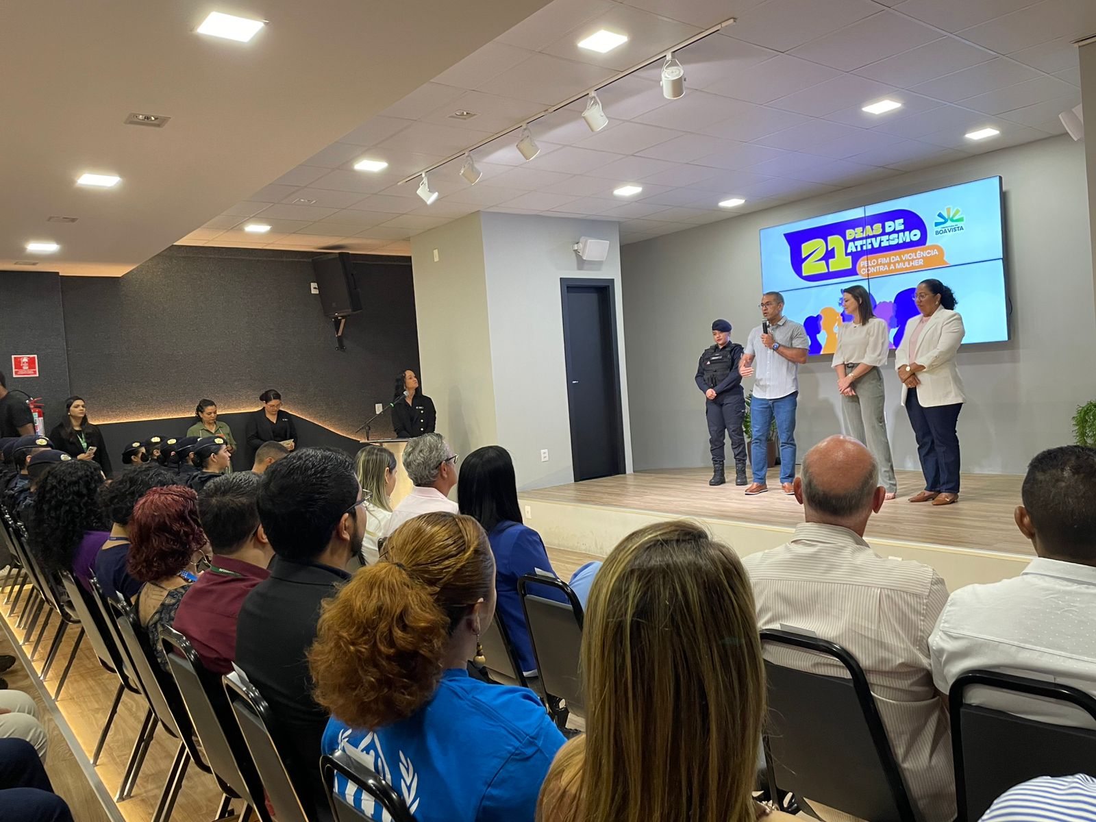  imagem colorida da cerimonia de lançamento no auditório da Prefeitura de Boa Vista. A frente há autoridades em pé falando ao microfone.