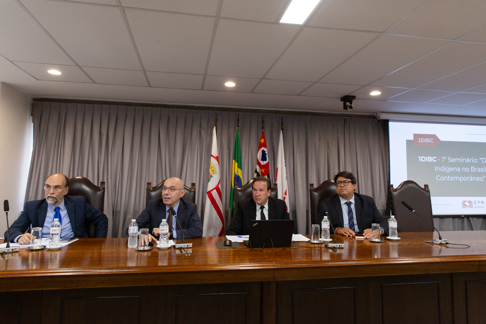 imagem colorida de uma mesa de autoridade durante o seminário