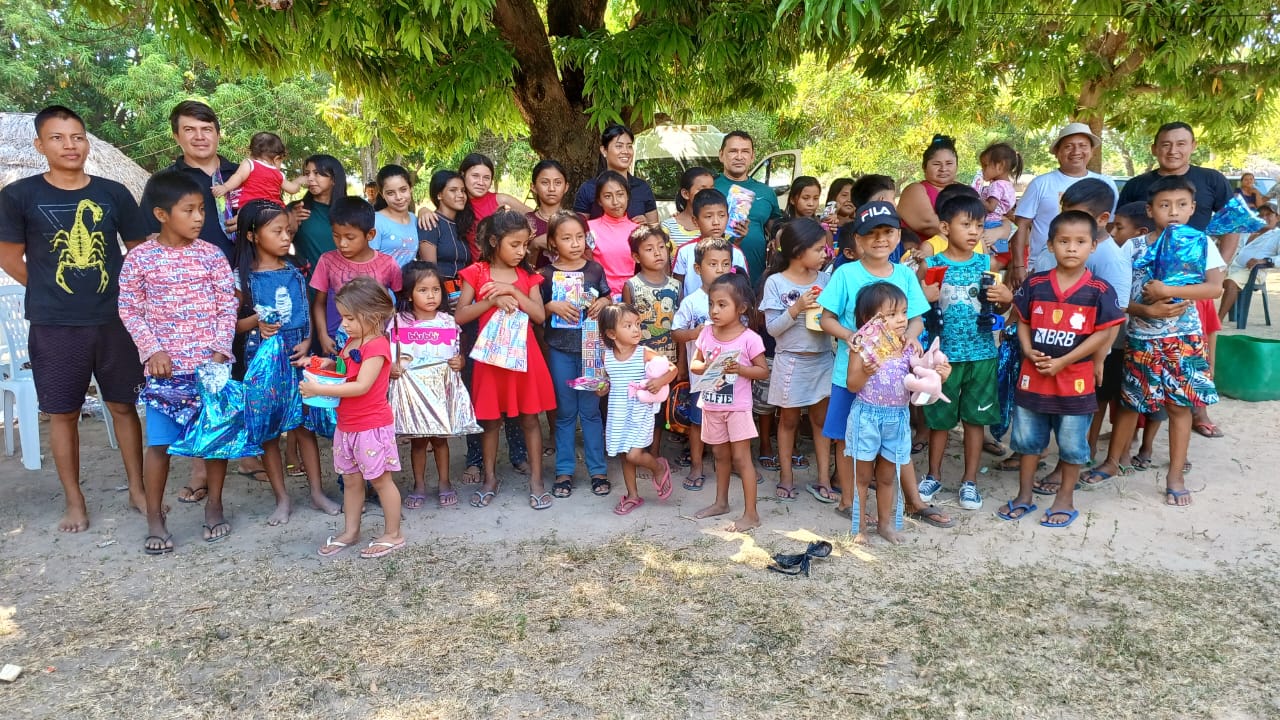foto colorida de crianças indigenas  reunidas segurando os presentes doados 
