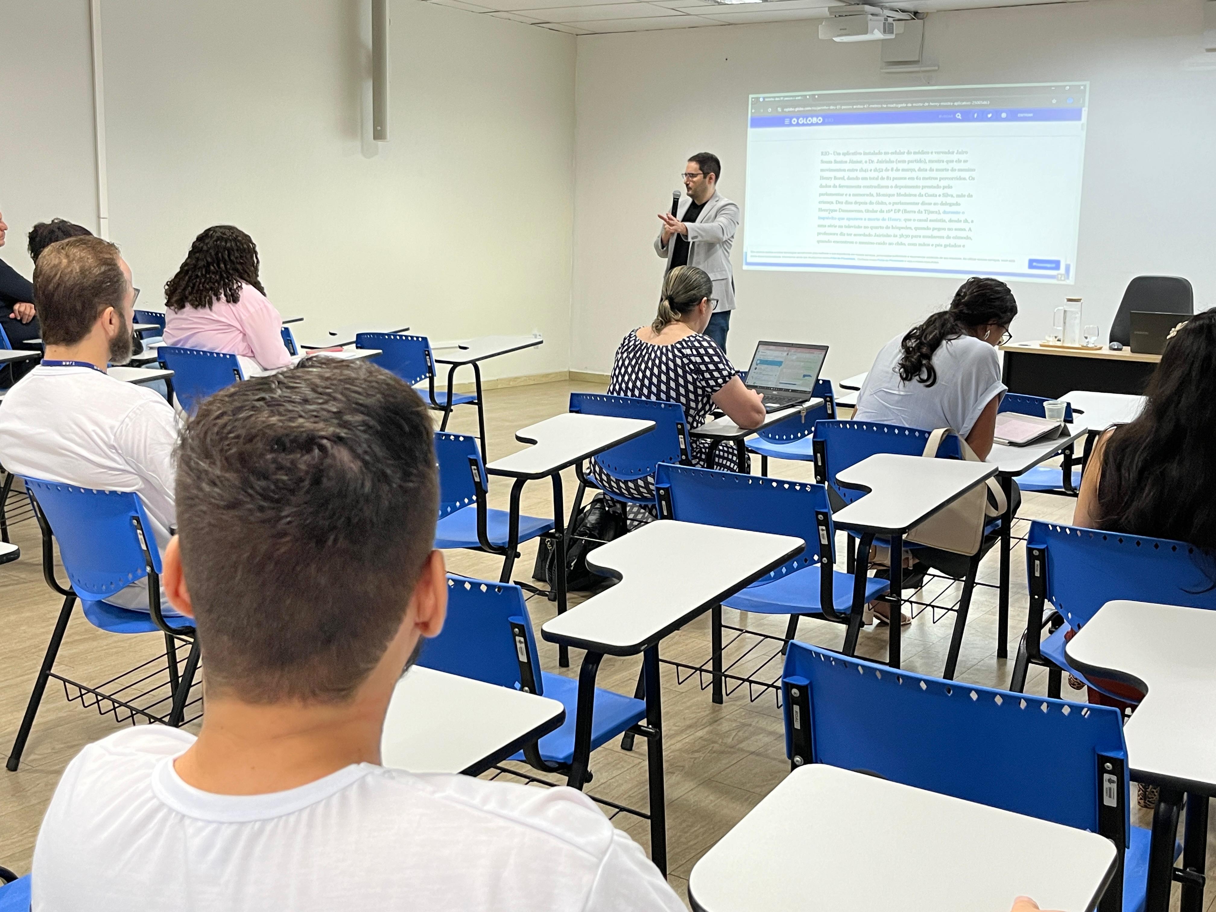 foto colorida de uma sala com cadeiras escolares ocupadas por servidores e  ministrando a palestra o especialista Bernardo de Azevedo