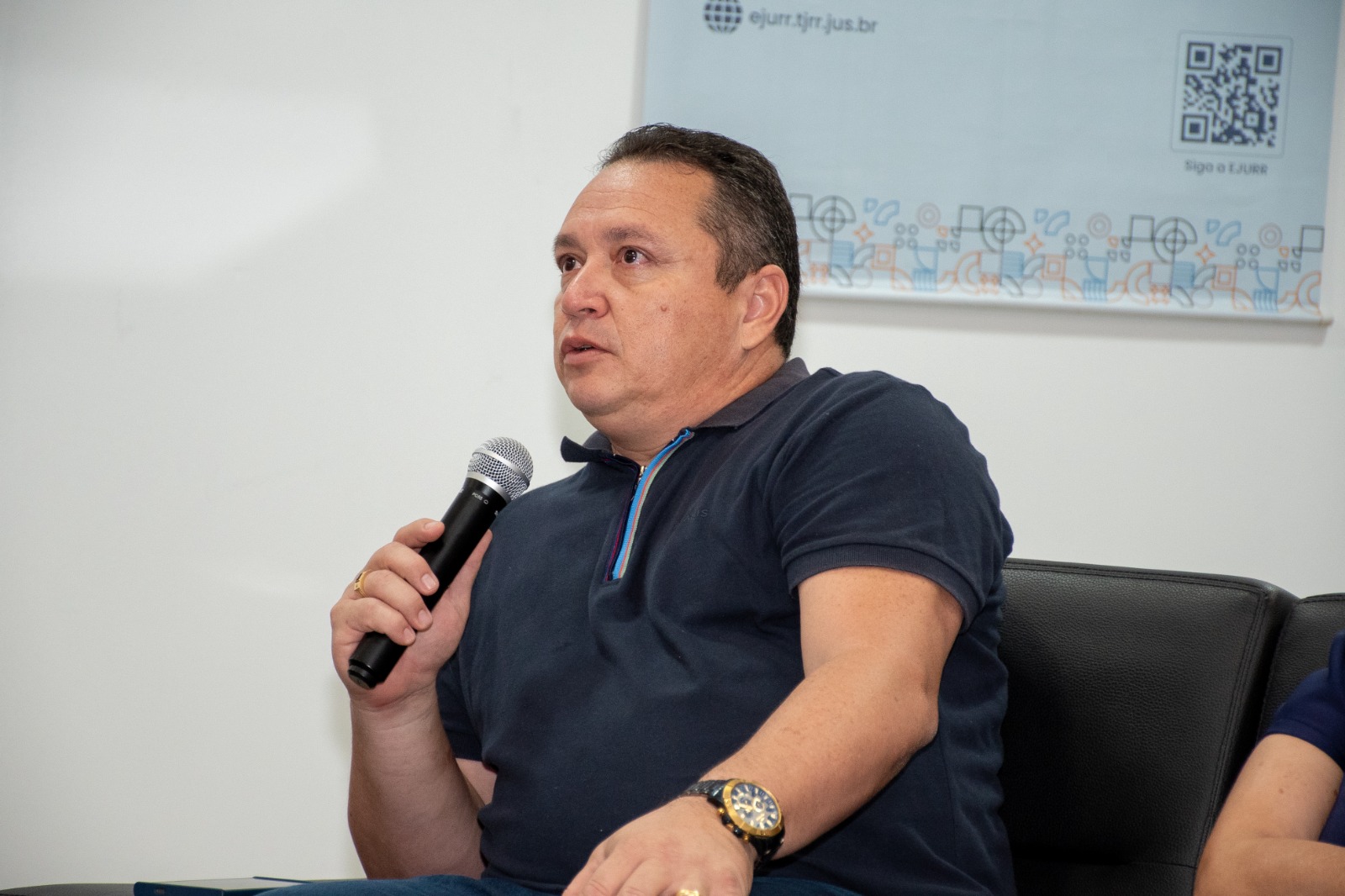 Foto colorida mostra o chefe do Setor de Acessibilidade e Inclusão, José Deodato, falando ao microfone durante a roda de conversa.