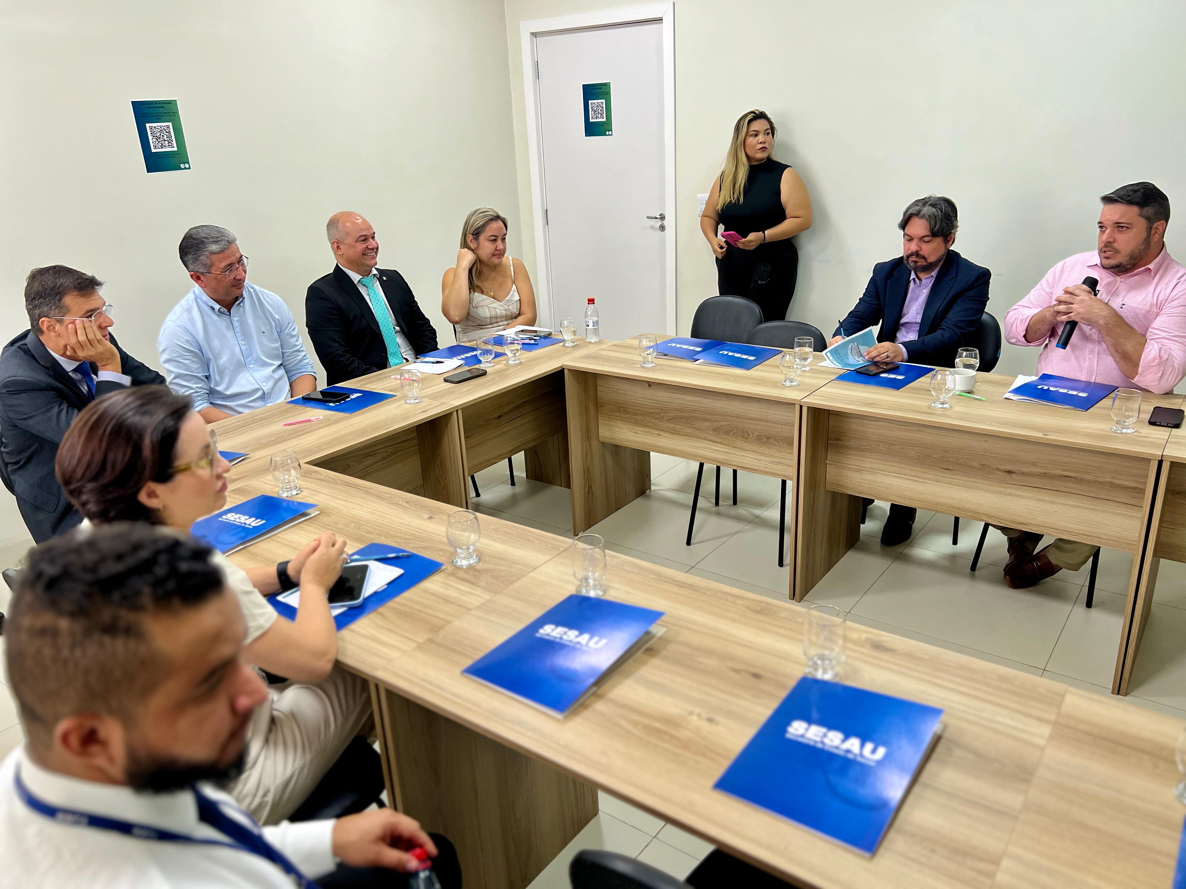 Imagem colorida mostra o juiz Eduardo Carvalho, coordenador do CES/RR,  reunido com nove autoridades da saúde em Roraima, sentados em volta de mesa de reunião posicionada em forma de “U”