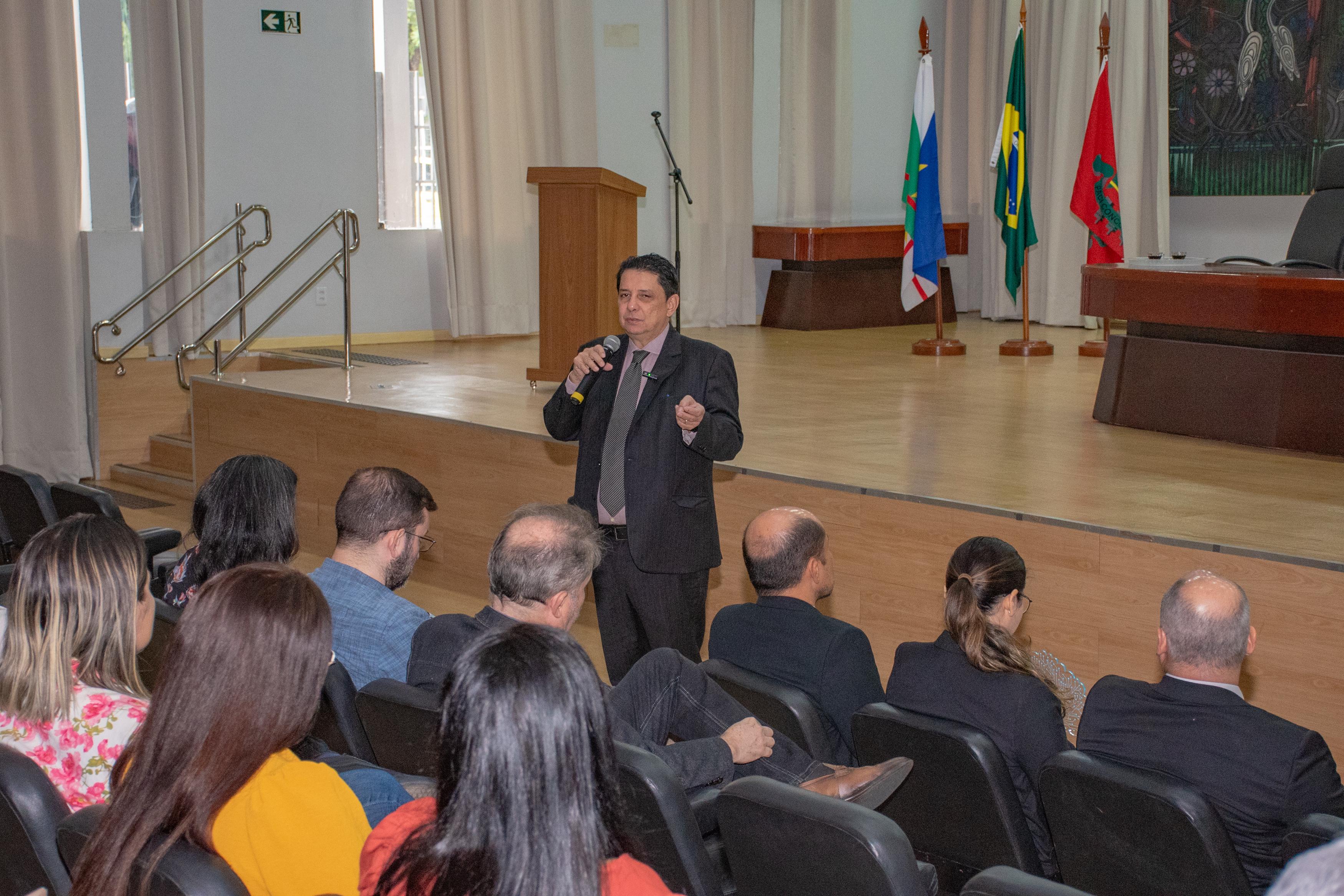 Imagem colorida mostra o presidente do TJRR, desembargador Jésus Nascimento, posando para fotografia ao lado de publico de magistrados, servidores, estagiários e colaboradores do TJRR, no auditório do Fórum Cível Advogado Sobral Pinto. Em suas mãos está o prêmio Excelência CNJ.