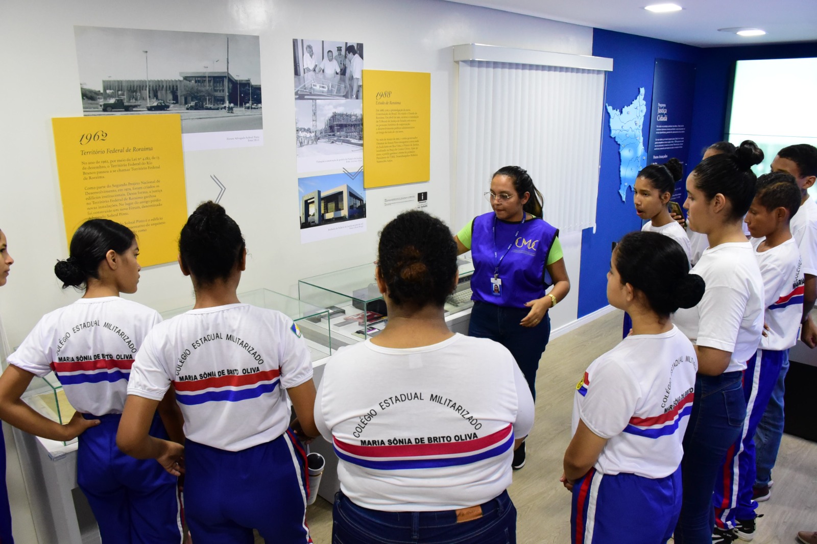  Imagem colorida mostra alunas e alunos do Colégio Estadual Militarizado Maria Sônia de Brito Oliva, durante visita assistida no Centro de Mémoria e Cultura.