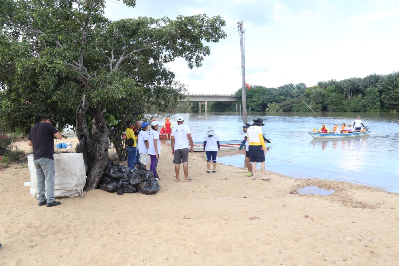 Pessoas reunidas na praia do Rio Branco fazendo a limpeza das águas